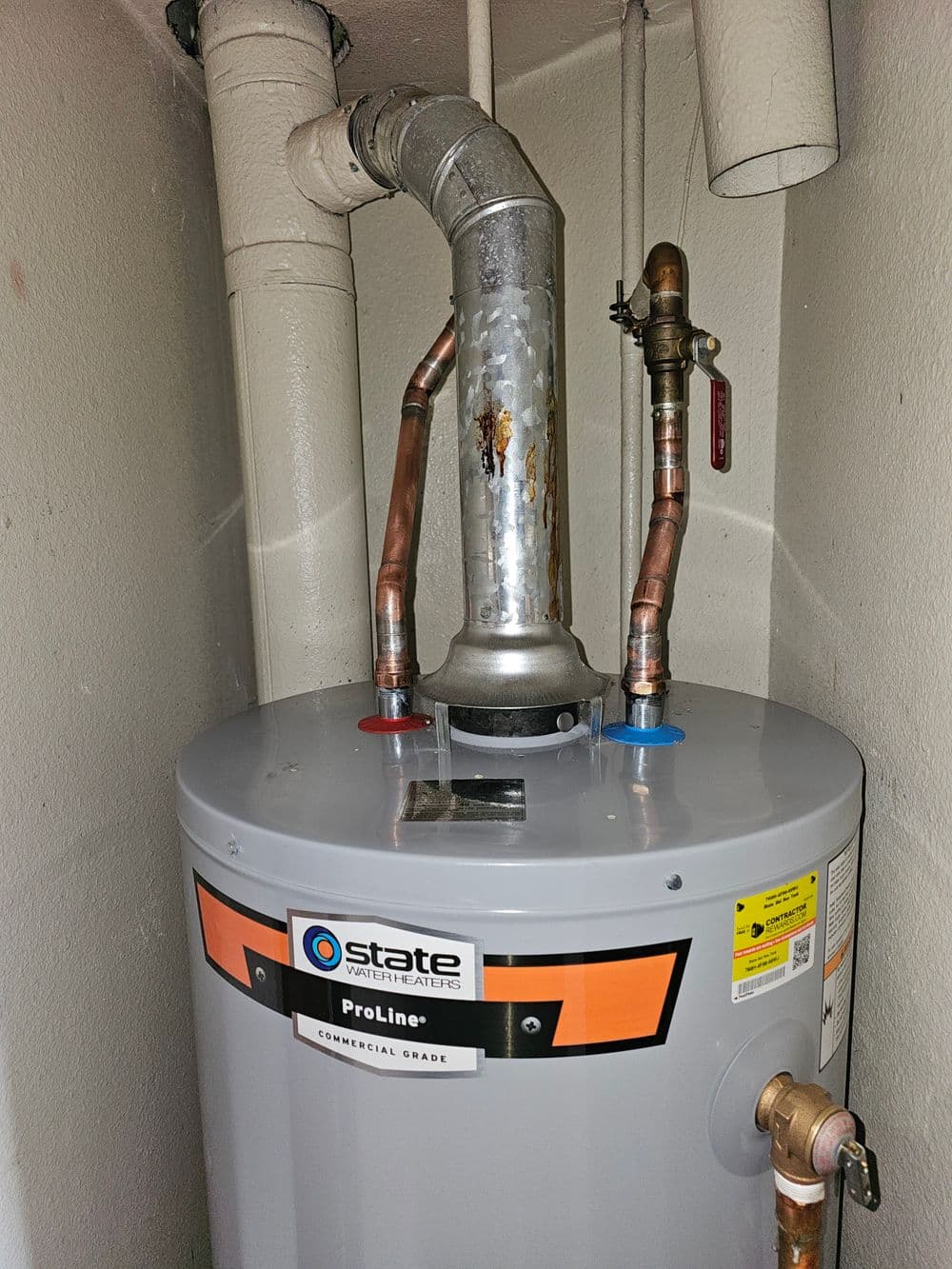 State ProLine commercial grade water heater with pipes and exhaust vent in utility room.